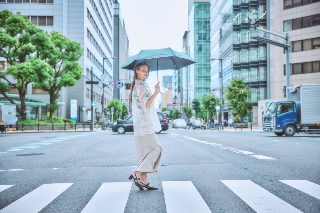 a.s.s.aの傘「ALL IN UMBRELLA」のUNISEXを持ちながら横断歩道を渡る外国人女性