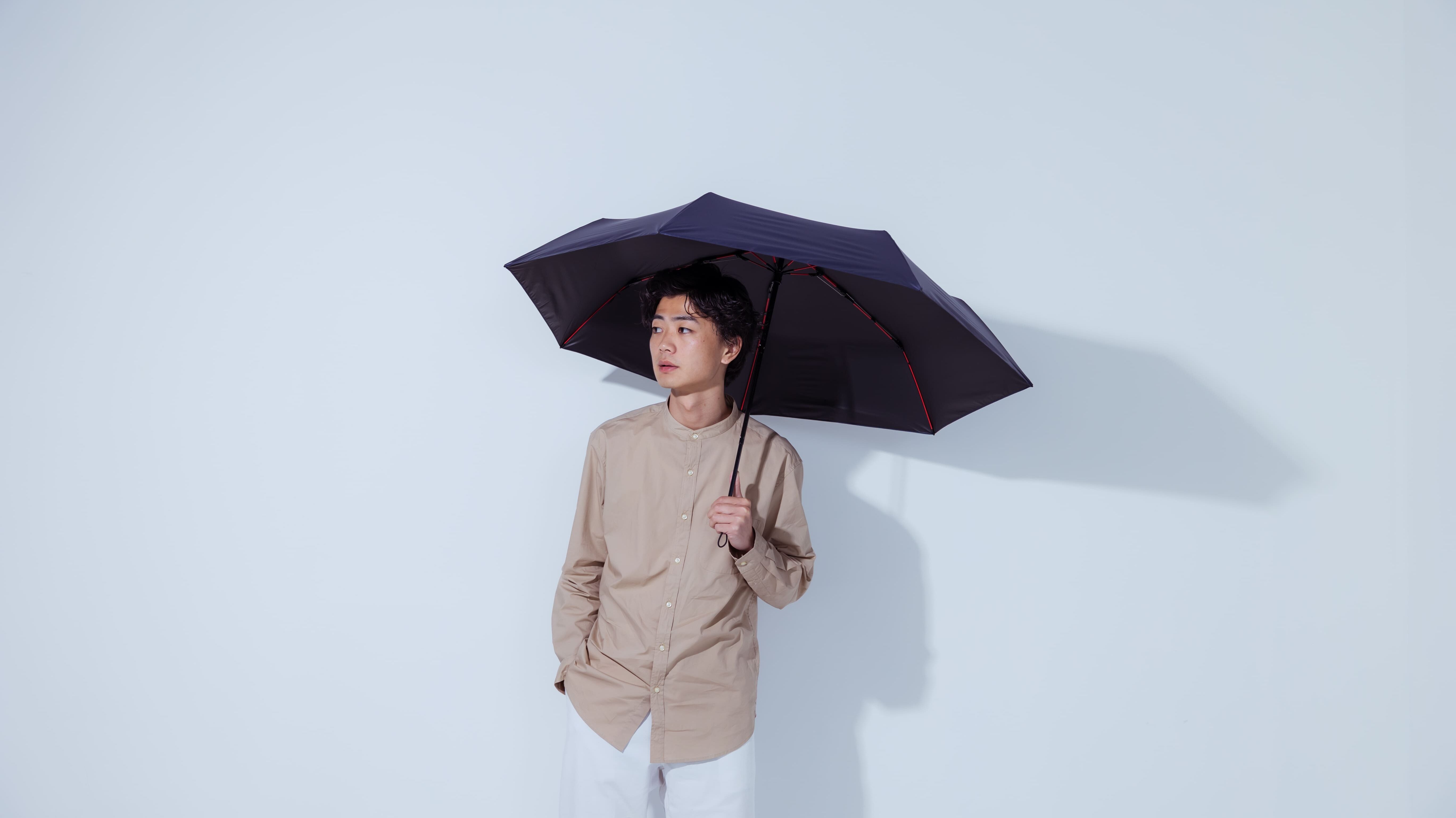 黒い傘を持って横を向く男性