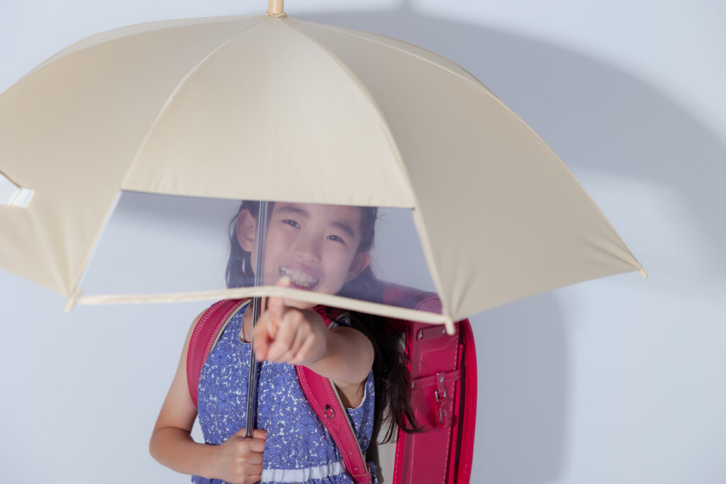 窓付きの傘を指さして笑う小学生