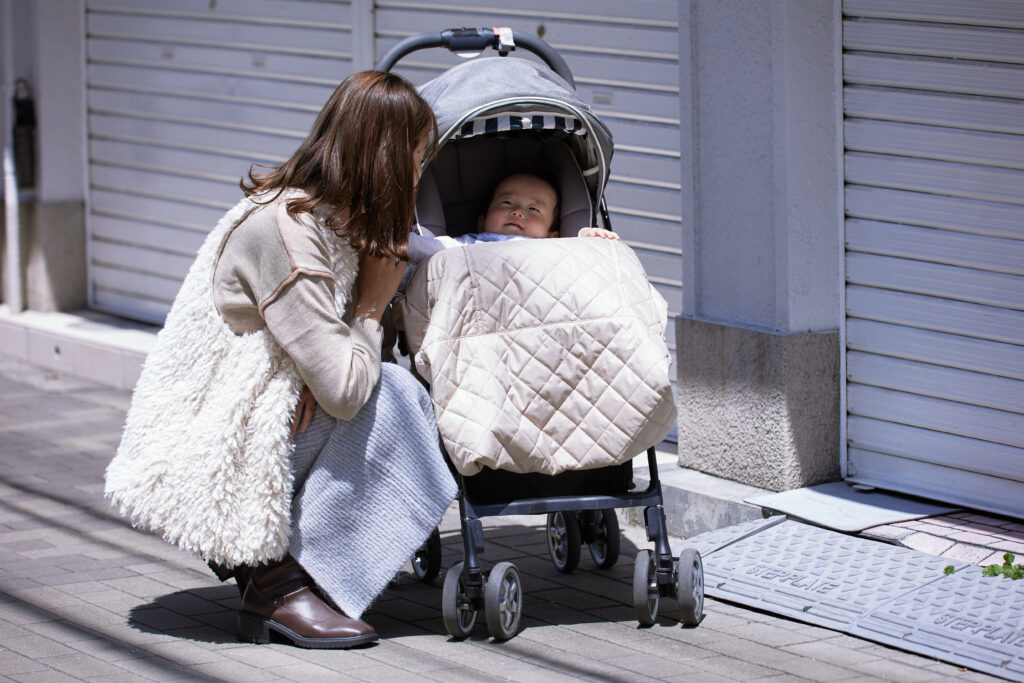 母親とベビーケープ付きのベビーカーに乗る赤ちゃん